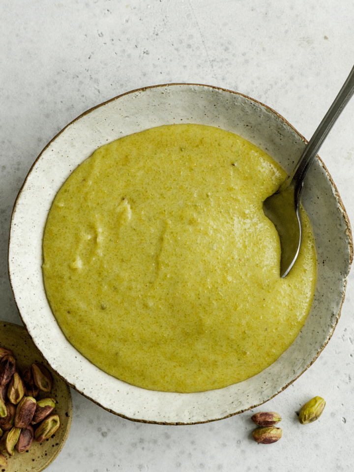 Pistachio cream in a bowl with a pistachios scattered around