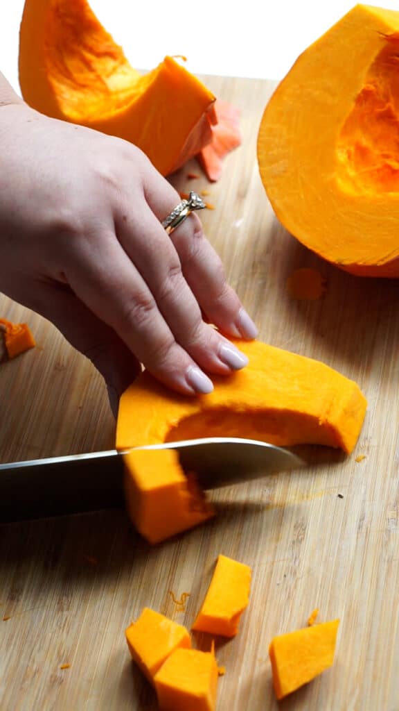 Action shot of cutting pumpkin into cubes with a knife
