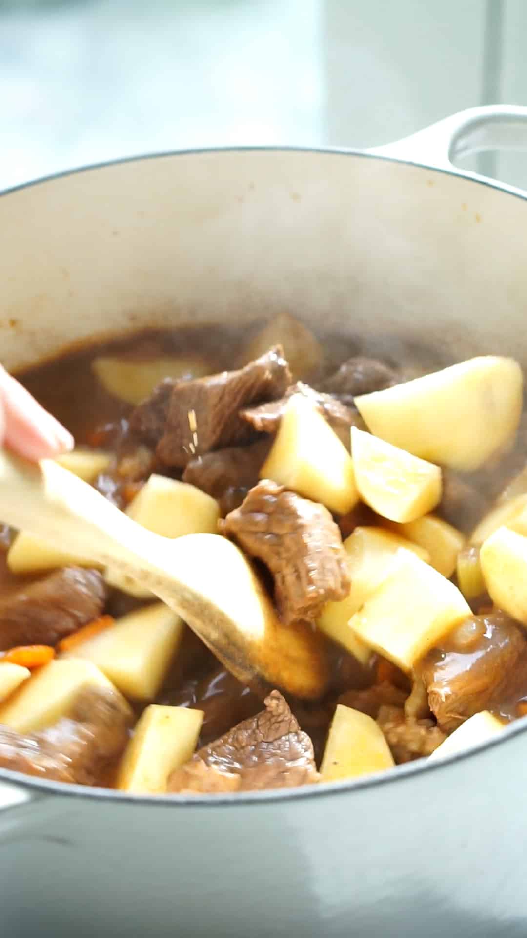 Italian beef stew process photo 5- adding potatoes to the pot with the beef