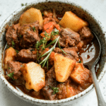 Bowl of Italian beef stew (spezzatino) topped with fresh rosemary and thyme