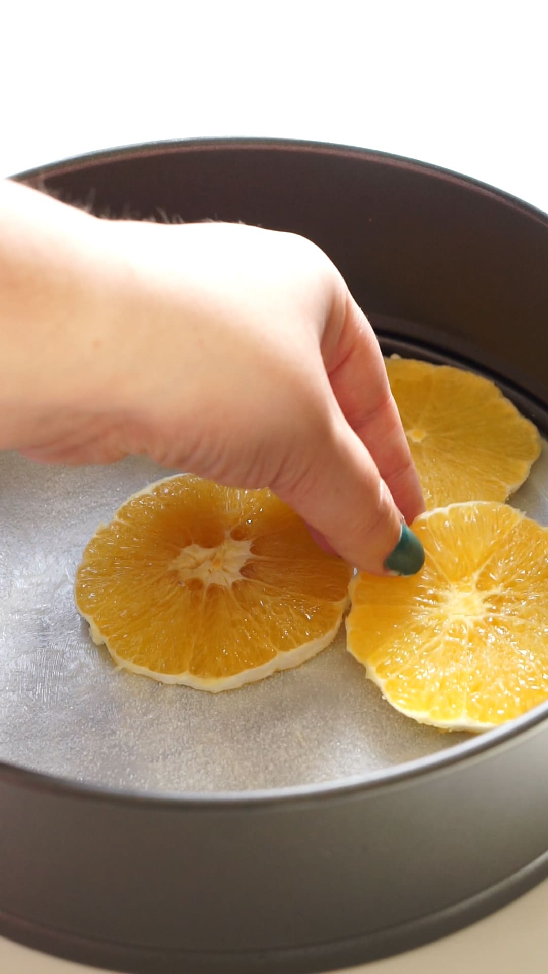 Putting oranges in cake pan for orange upside down cake