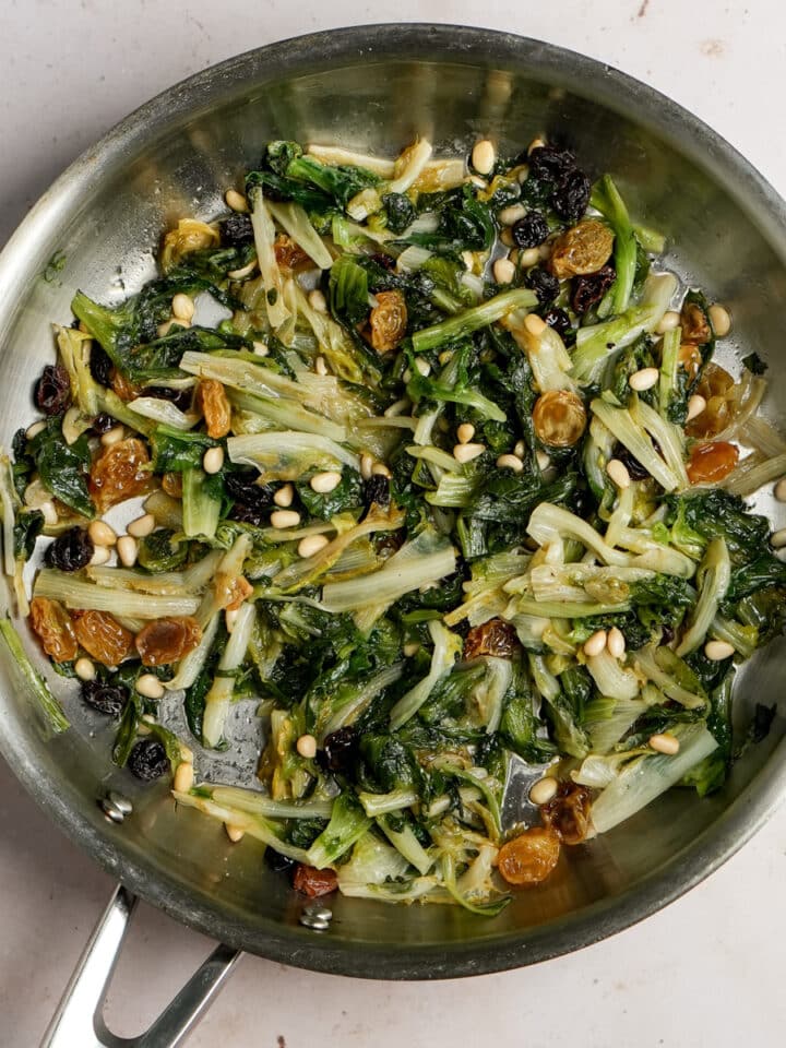 Escarole with raisins and pine nuts in a pan