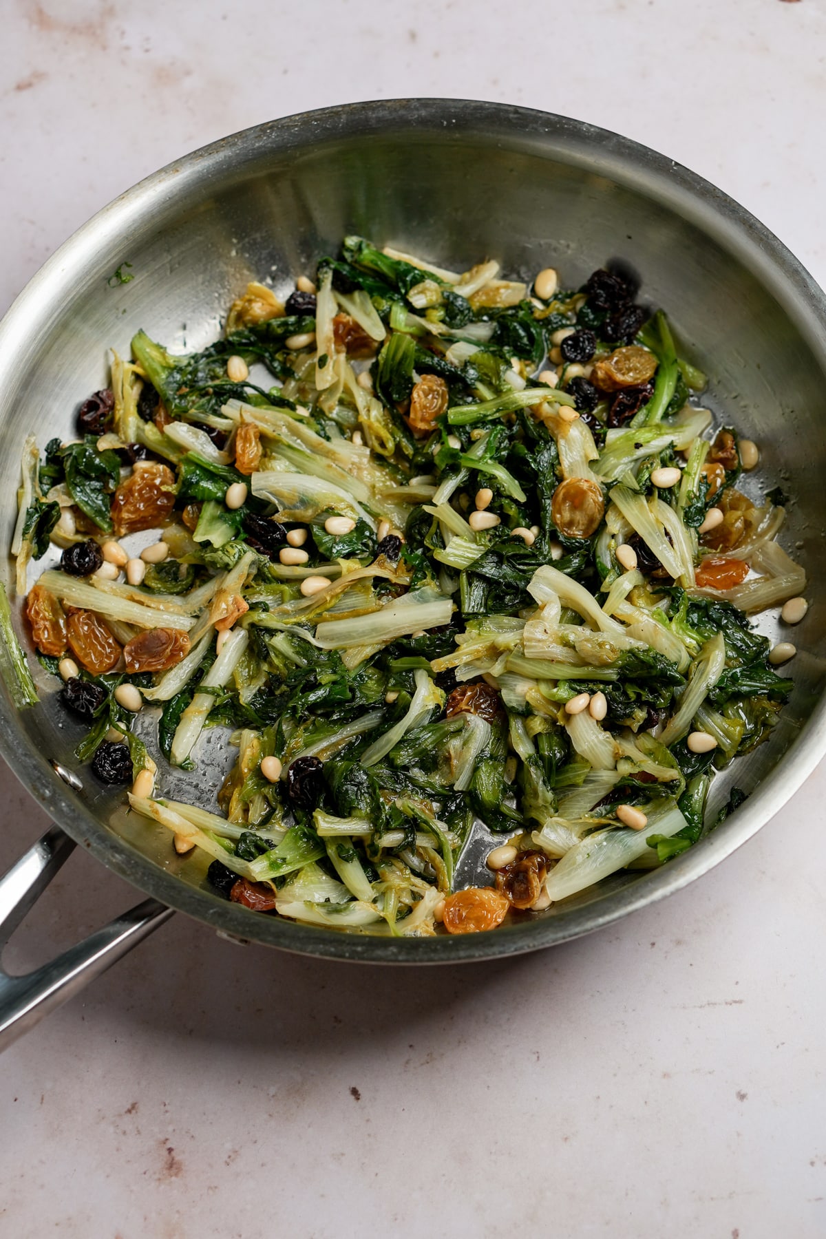 Escarole with raisins and pine nuts in a pan