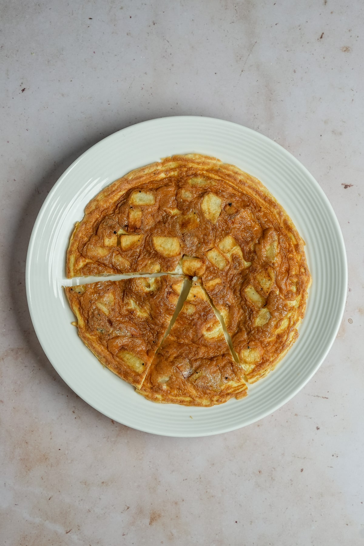 Potato frittata in a white plate with two pieces cut out