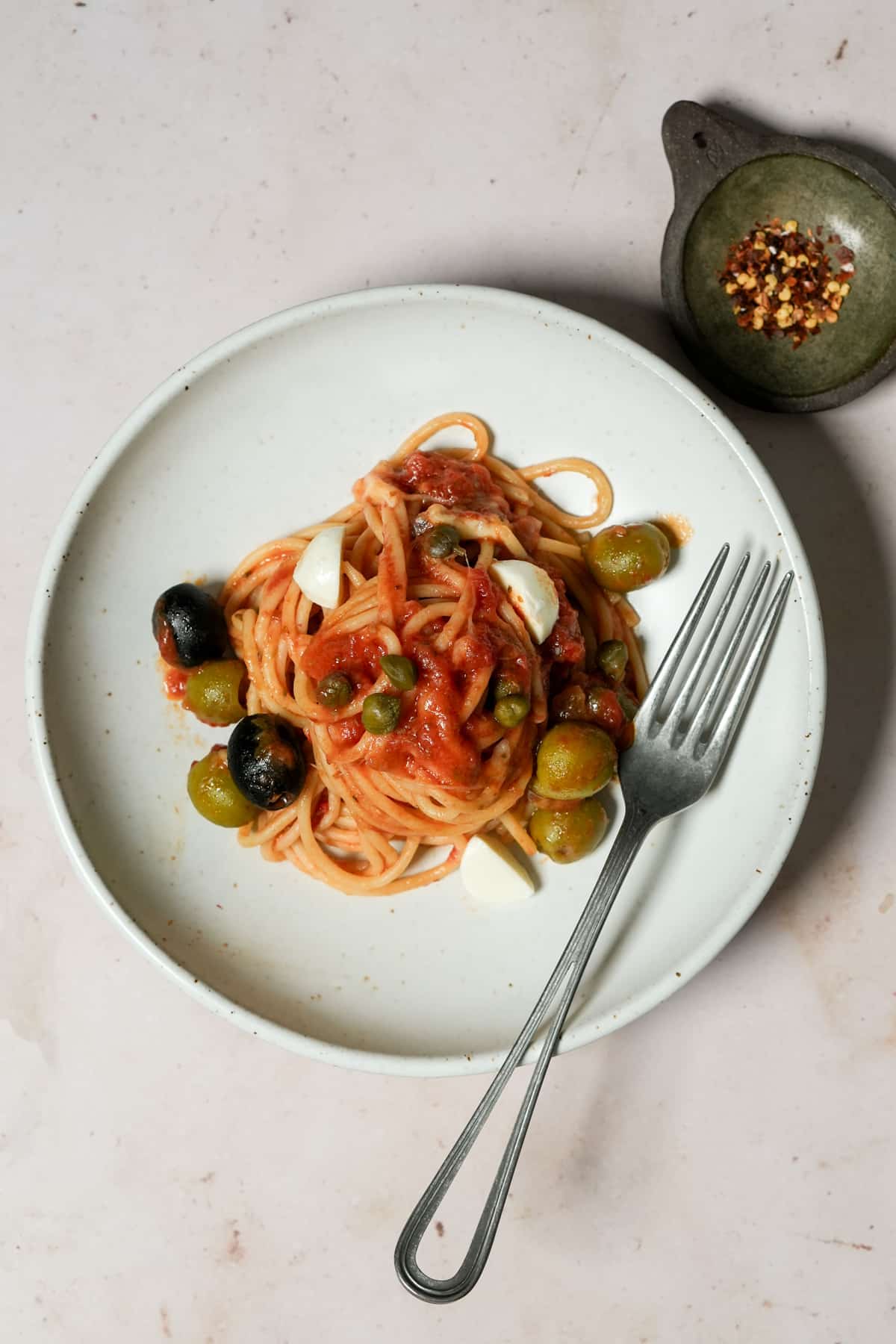 Vesuviana pasta topped with capers, olives and mozzarella in a plate