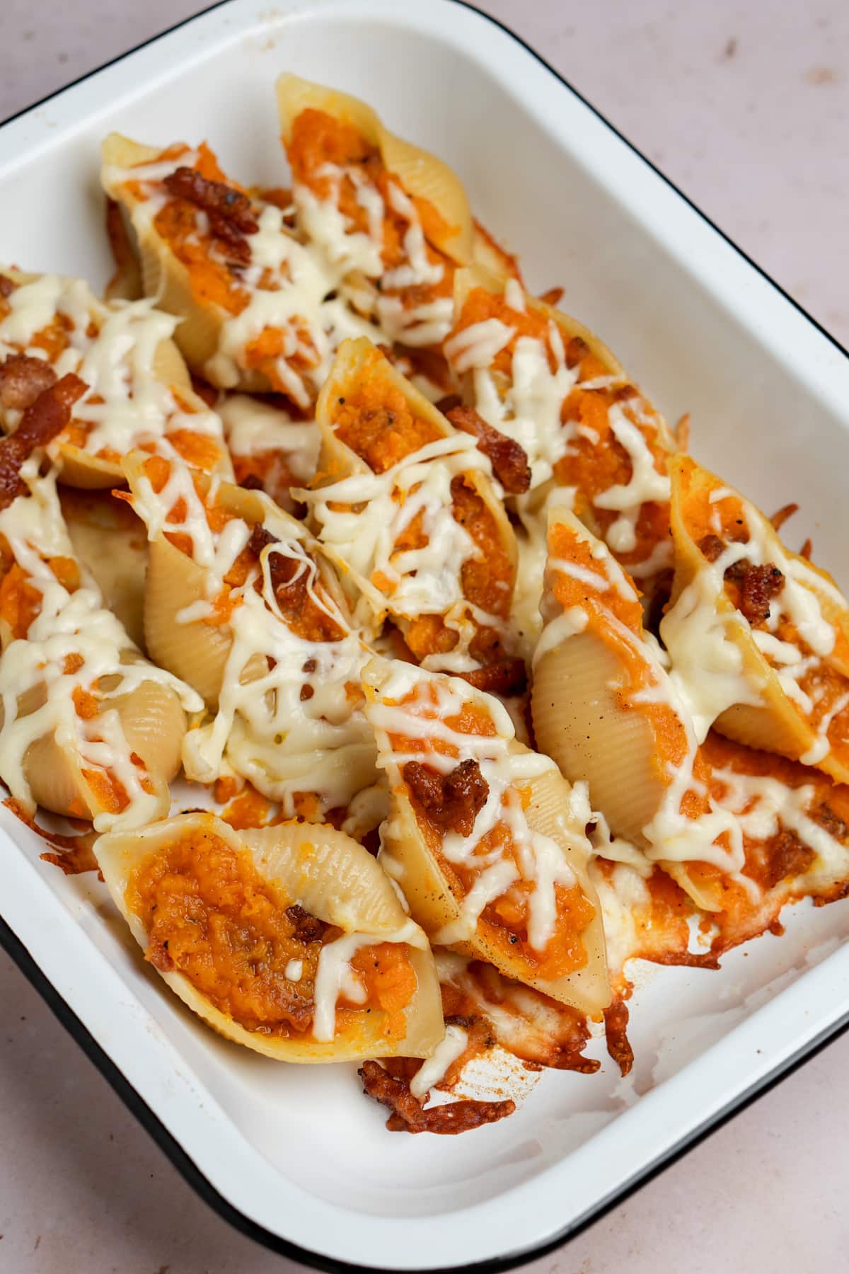Butternut squash stuffed shells topped with mozzarella in a baking dish