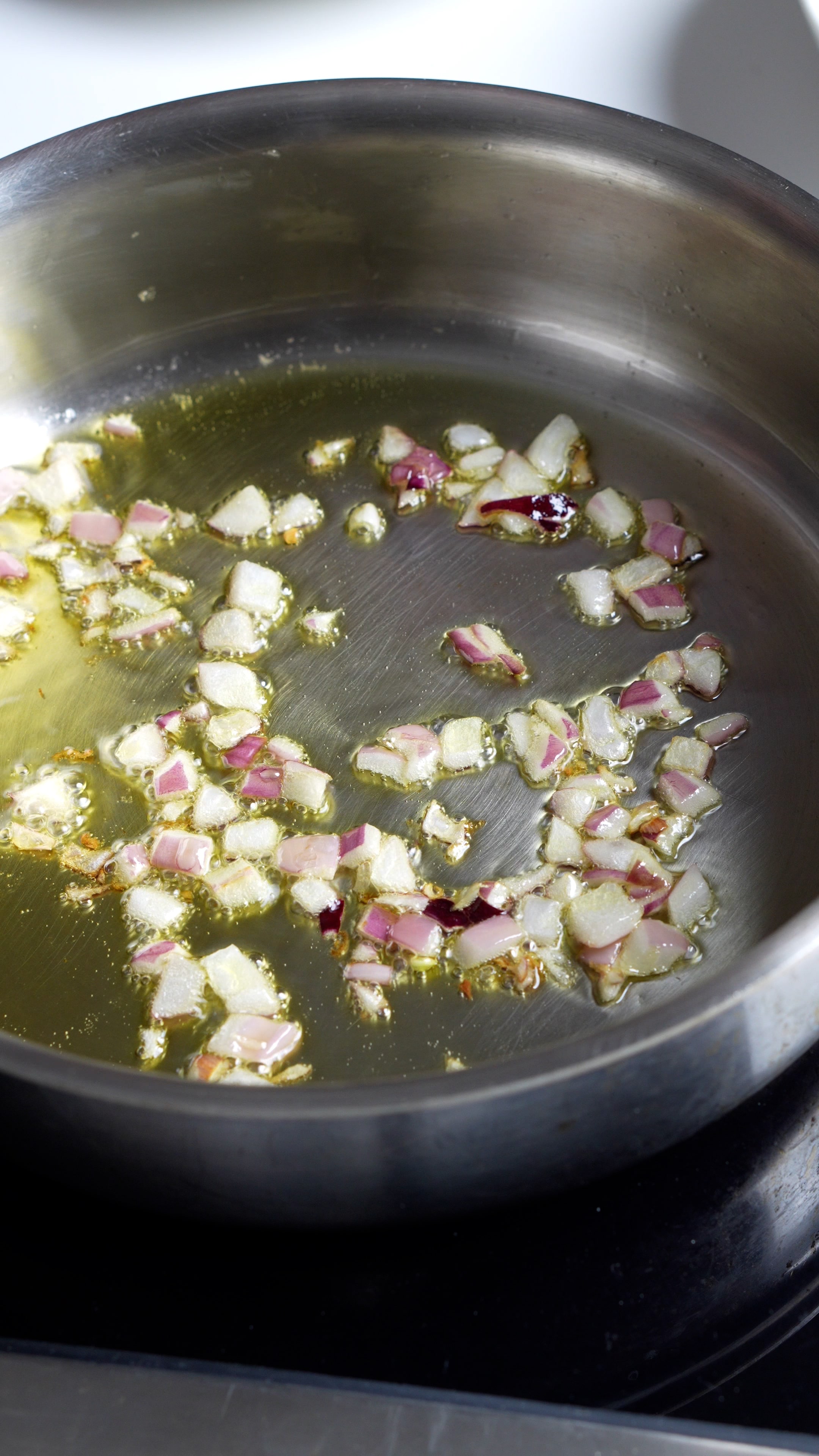 Step by step process on how to make vesuviana pasta (step 1) - Diced up red onion in a pan with olive oil