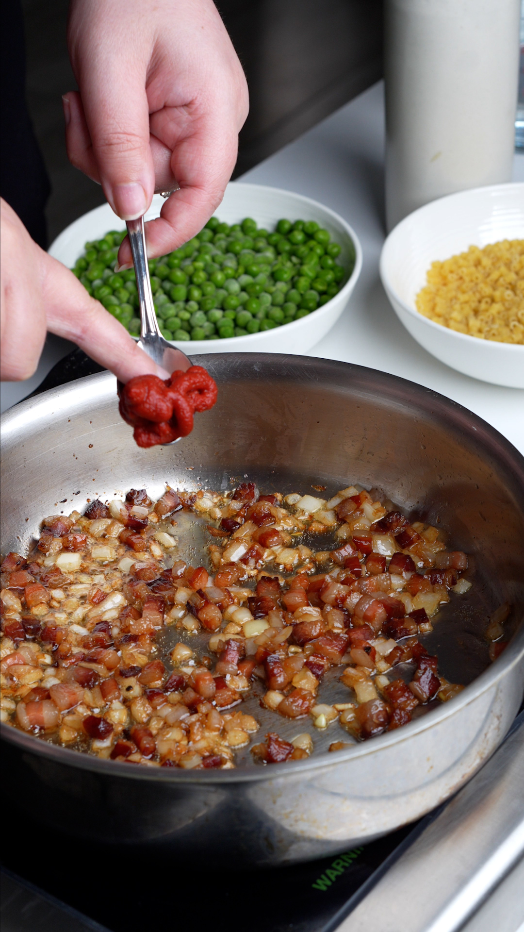 Process photo on how to make pasta e piselli - sauteed pancetta and onion in a pan
