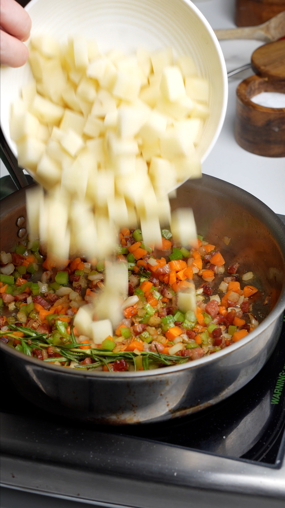 Cubed potatoes being added to pan