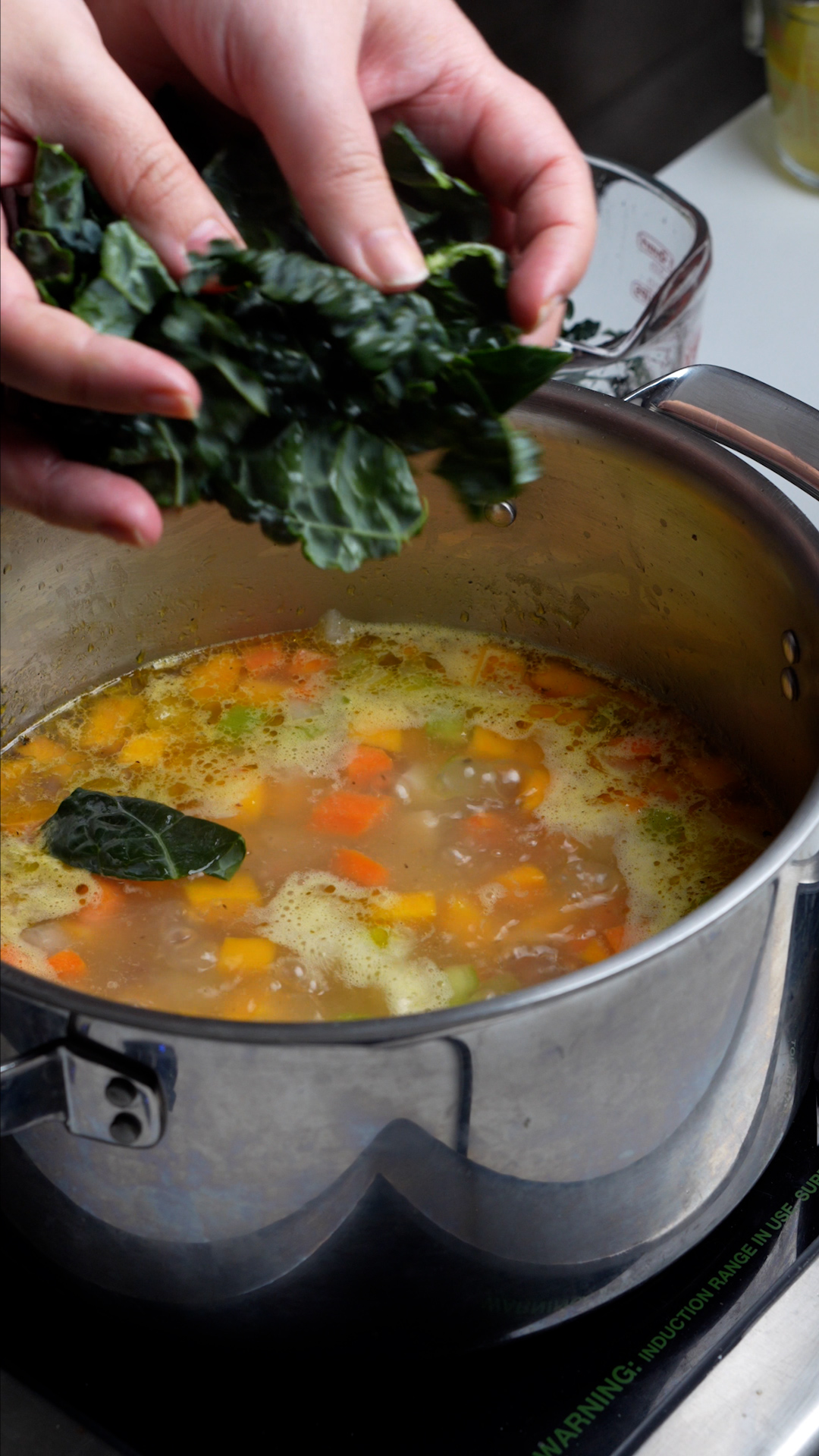 Step by step photos on how to make vegetarian soup with rice - lacinato kale being added to the pot
