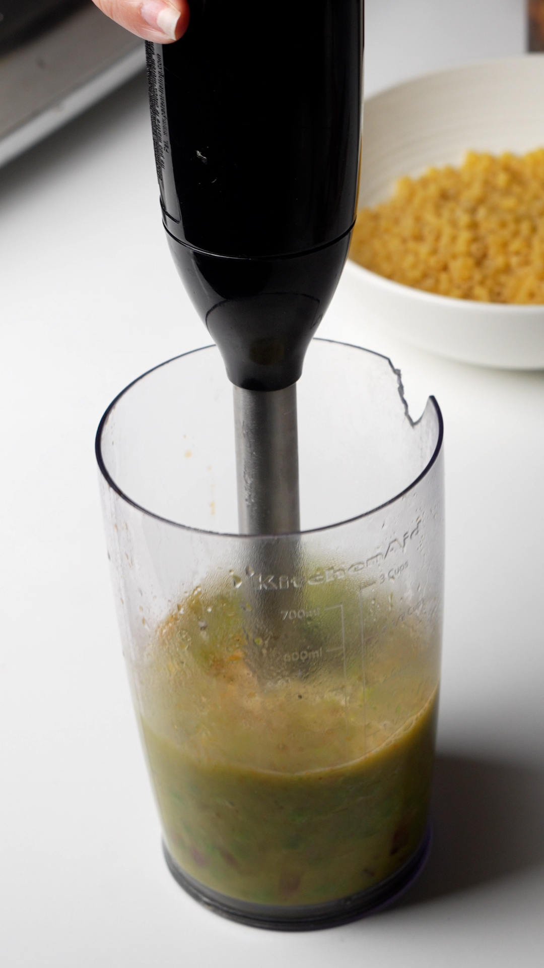 Process photo on how to make pasta e piselli - pea mixture being blended with immersion blender