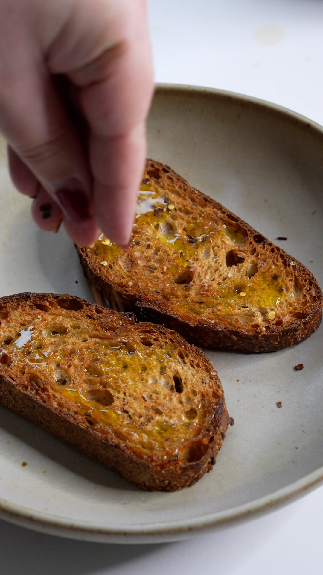 Toasted sourdough bread in a bowl being topped with salt
