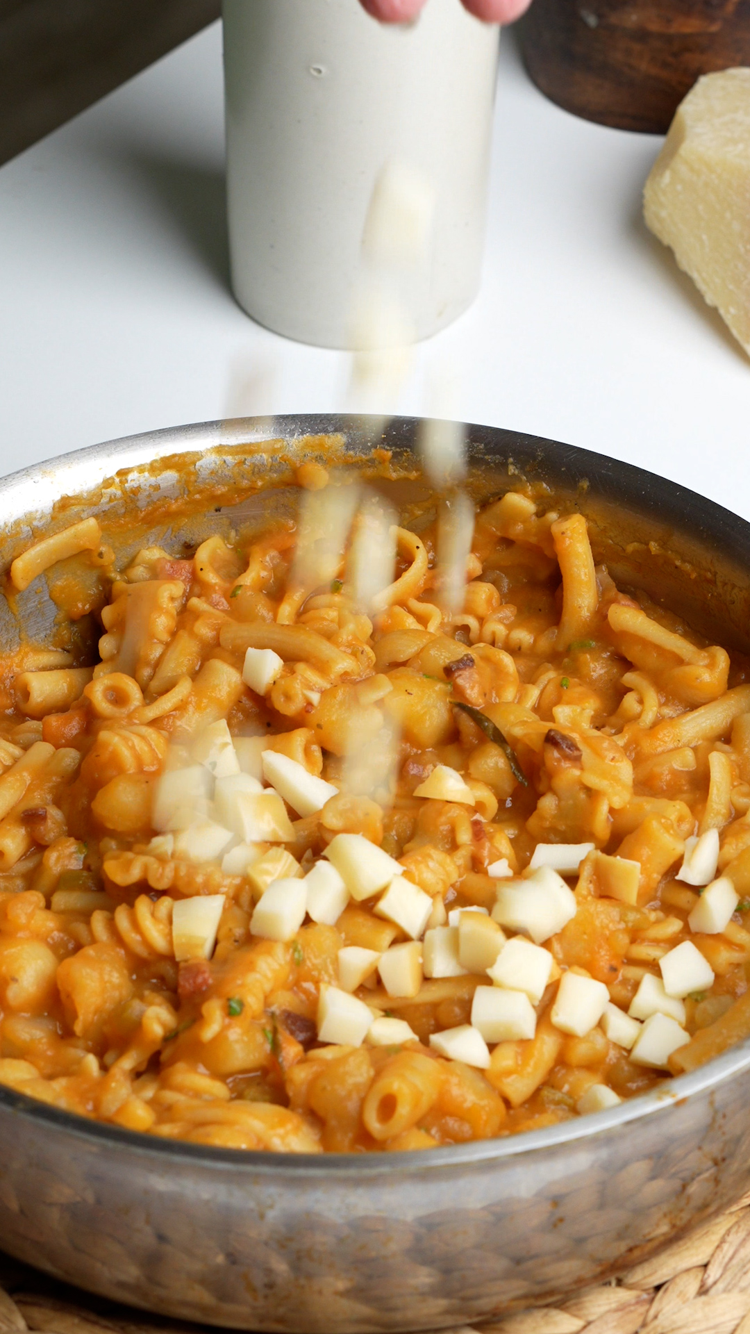 Scamorza cheese being added to pan with pasta e patate in it