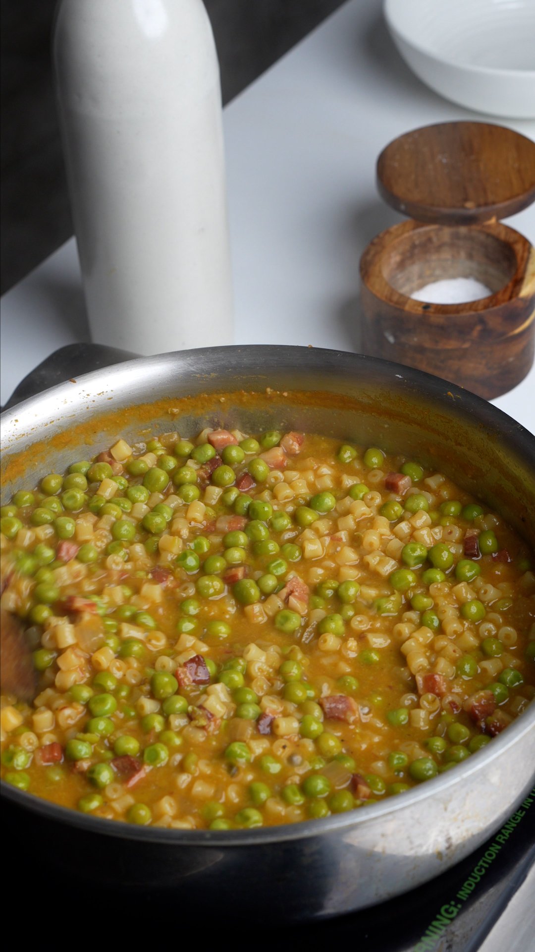 Process photo on how to make pasta e piselli - pasta e piselli being stirred in a pan