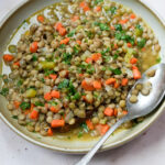 Bowl of carrot and lentil soup topped with chopped parsley