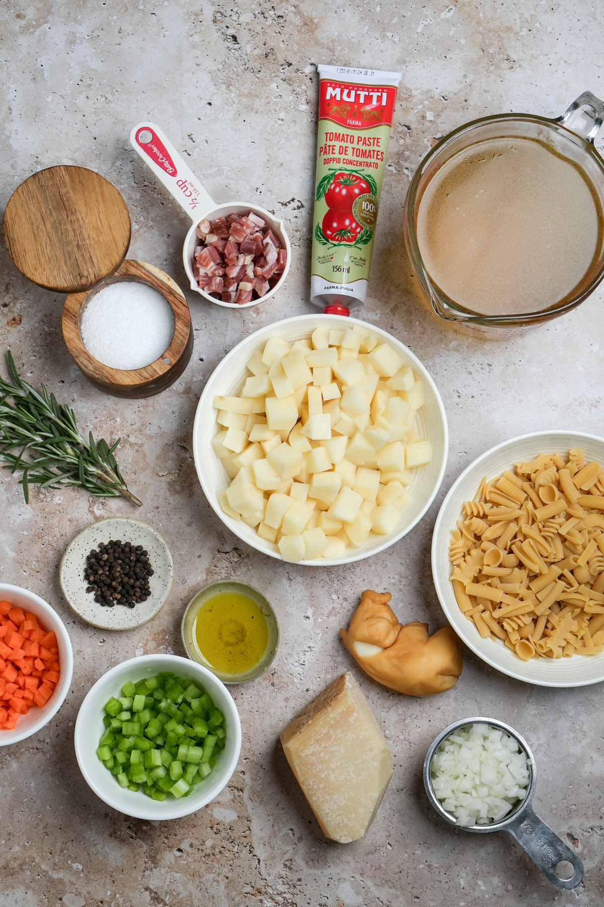 Ingredients for pasta e patate - tomato paste, vegetable stock, pasta mista, scamorza, onion, parmigiano reggiano, potatoes, celery, carrots, olive oil, pepper, rosemary, salt, pancetta