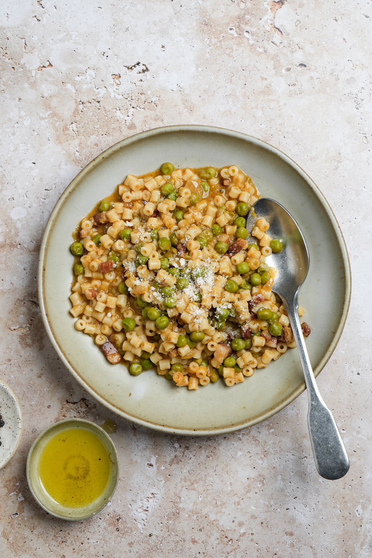 Plate of pasta e piselli with a small bowl of olive oil to the side