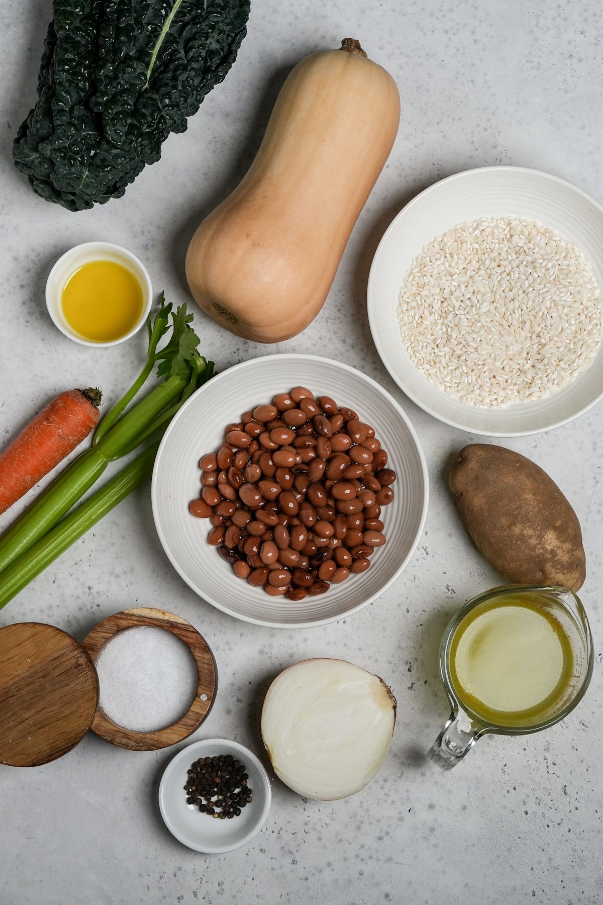 Ingredients for vegetarian soup with rice - lacinato kale, butternut squash, rice, potato, vegetable stock, onion, pepper, salt, beans, celery, carrot, olive oil