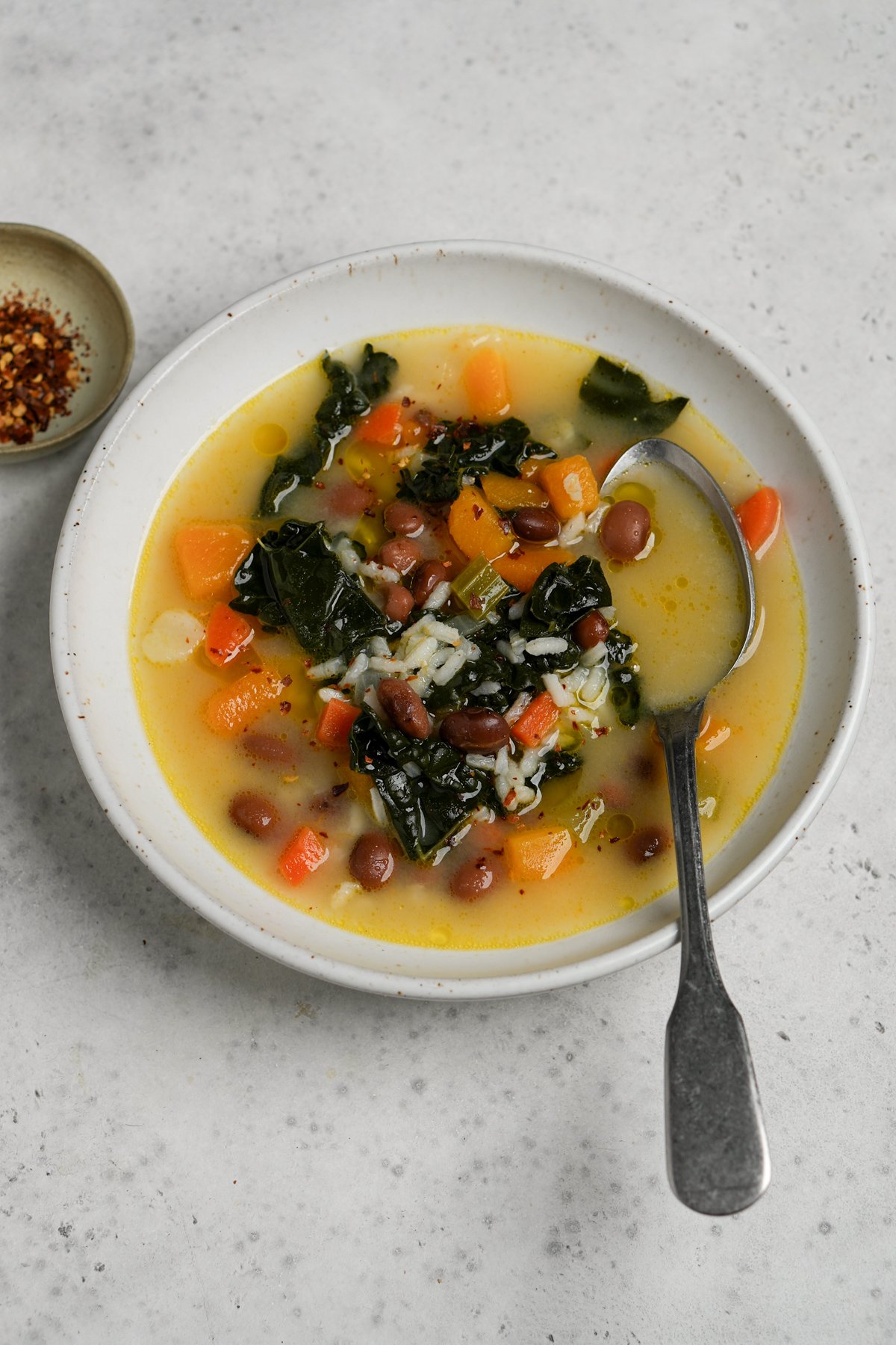 Vegetarian soup with rice in a bowl with a small dish of chili pepper in the background