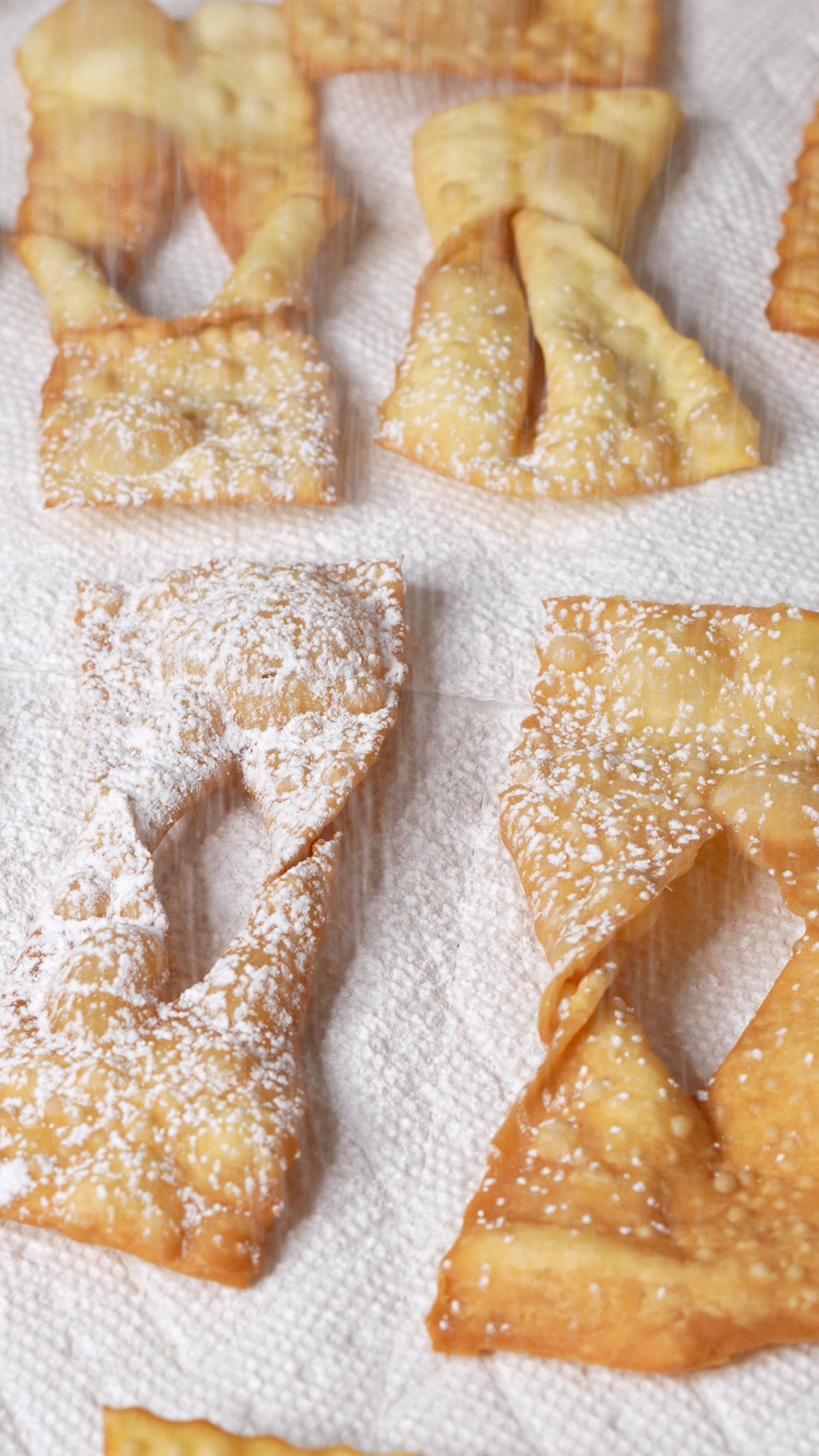 Powdered sugar getting sprinkled onto fried chiacchiere