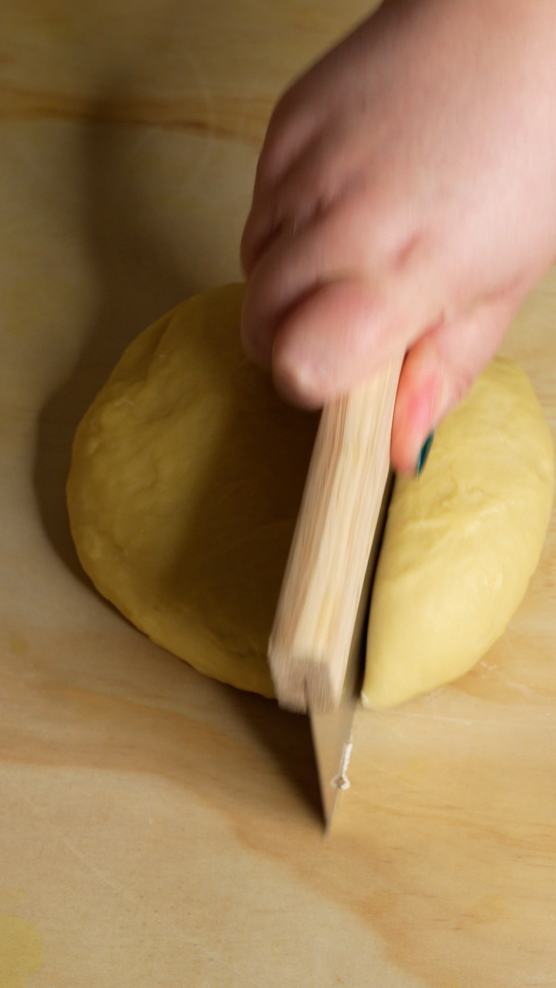 Dough ball being cut with a bench scraper