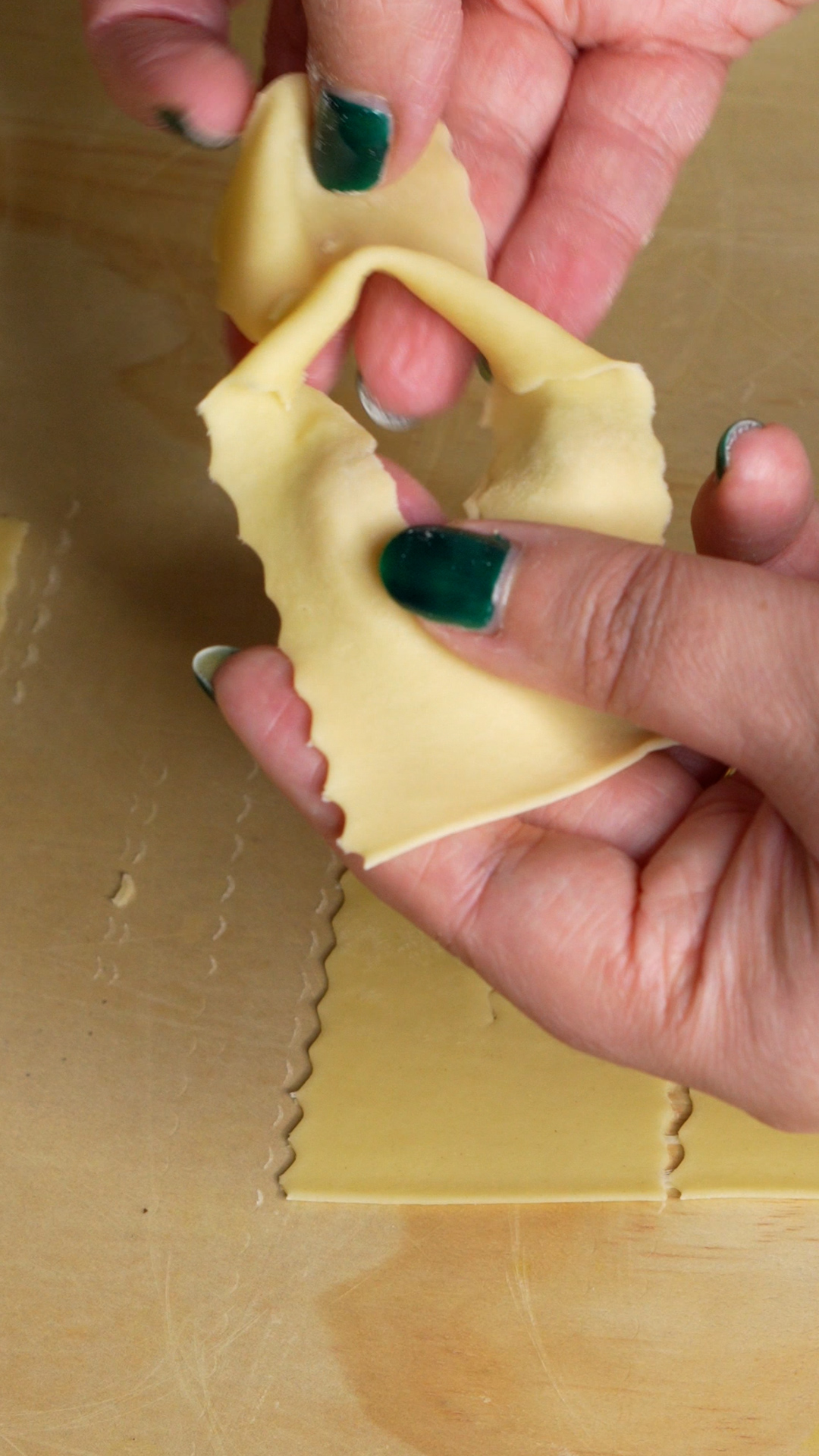 Shaping chiacchiere - two hands forming the piece of dough into bows
