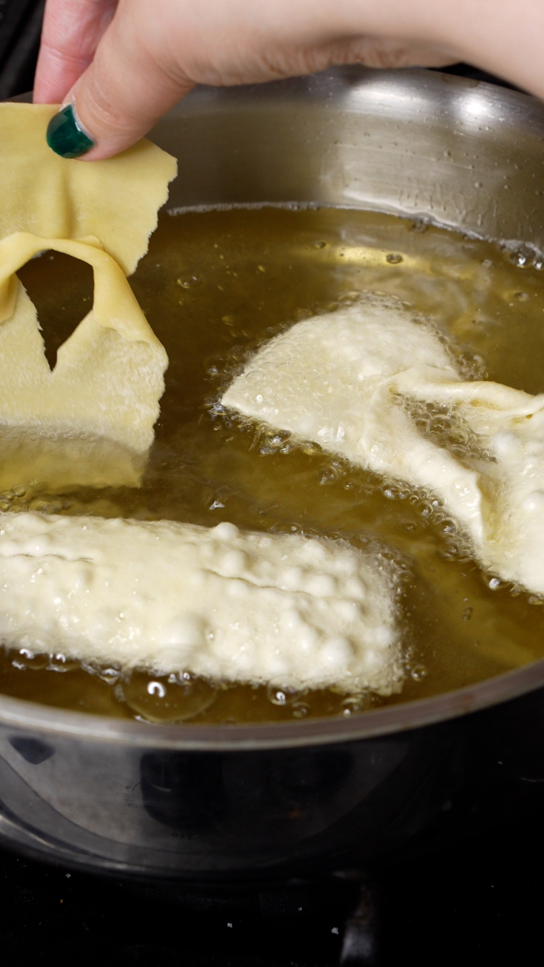 Chiacchiere being fried in a pan in hot oil