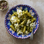 Italian pistachio pasta in a bowl topped with burrata with a small bowl of pistachios to the side