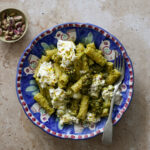Italian pistachio pasta topped with burrata in a plate with a fork in it