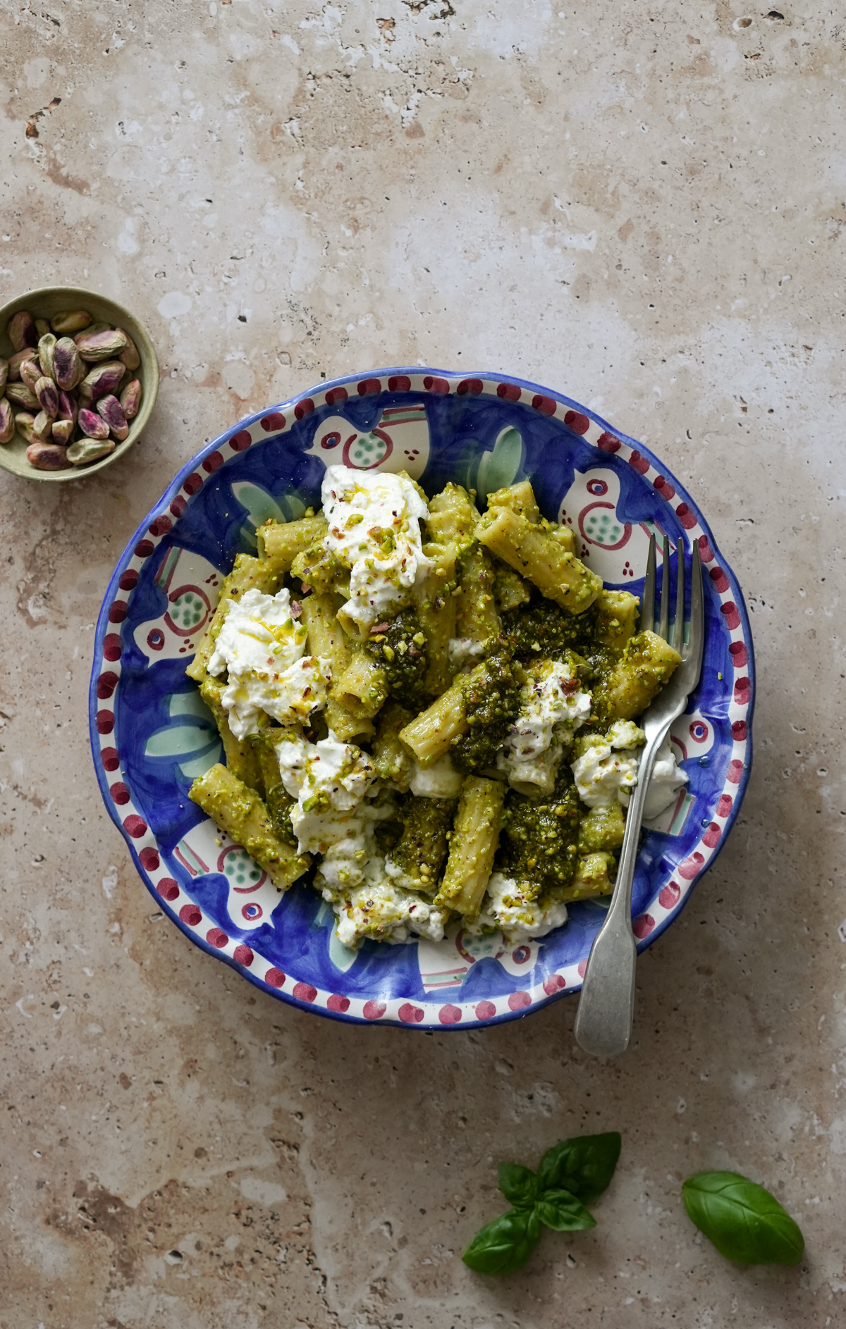 Italian pistachio pasta topped with burrata in a plate with a fork in it