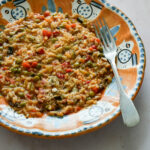 Vegetable risotto in an orange dish with a fork