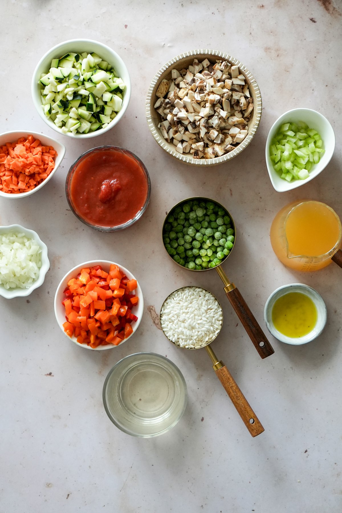 Vegetable risotto ingredients - mushrooms, celery, vegetable broth, olive oil, peas, arborio rice, white wine, peppers, onions, tomato passata, onions, carrots, zucchini