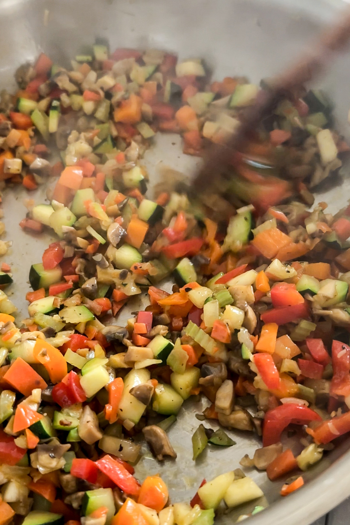 Chopped mixed vegetables being stirred in a pan