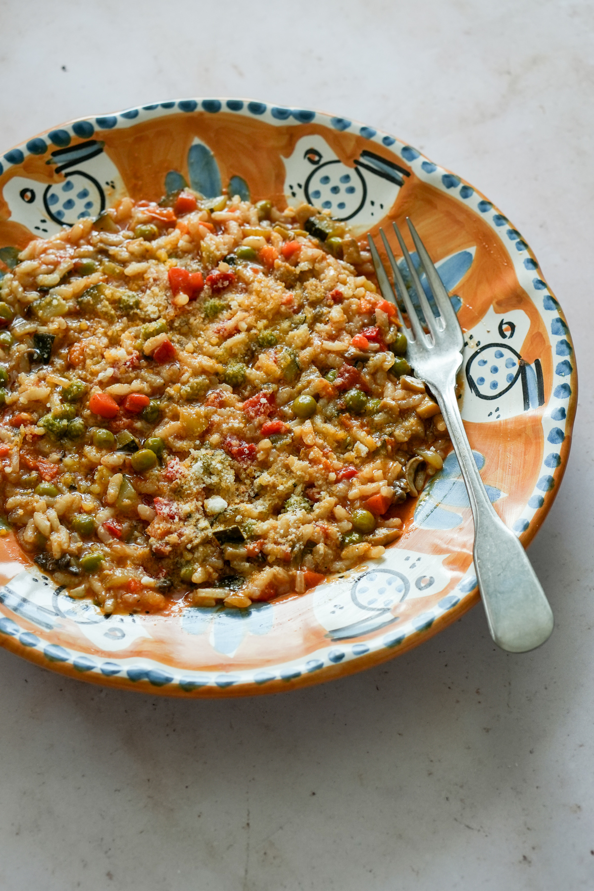 Vegetable risotto in an orange dish with a fork