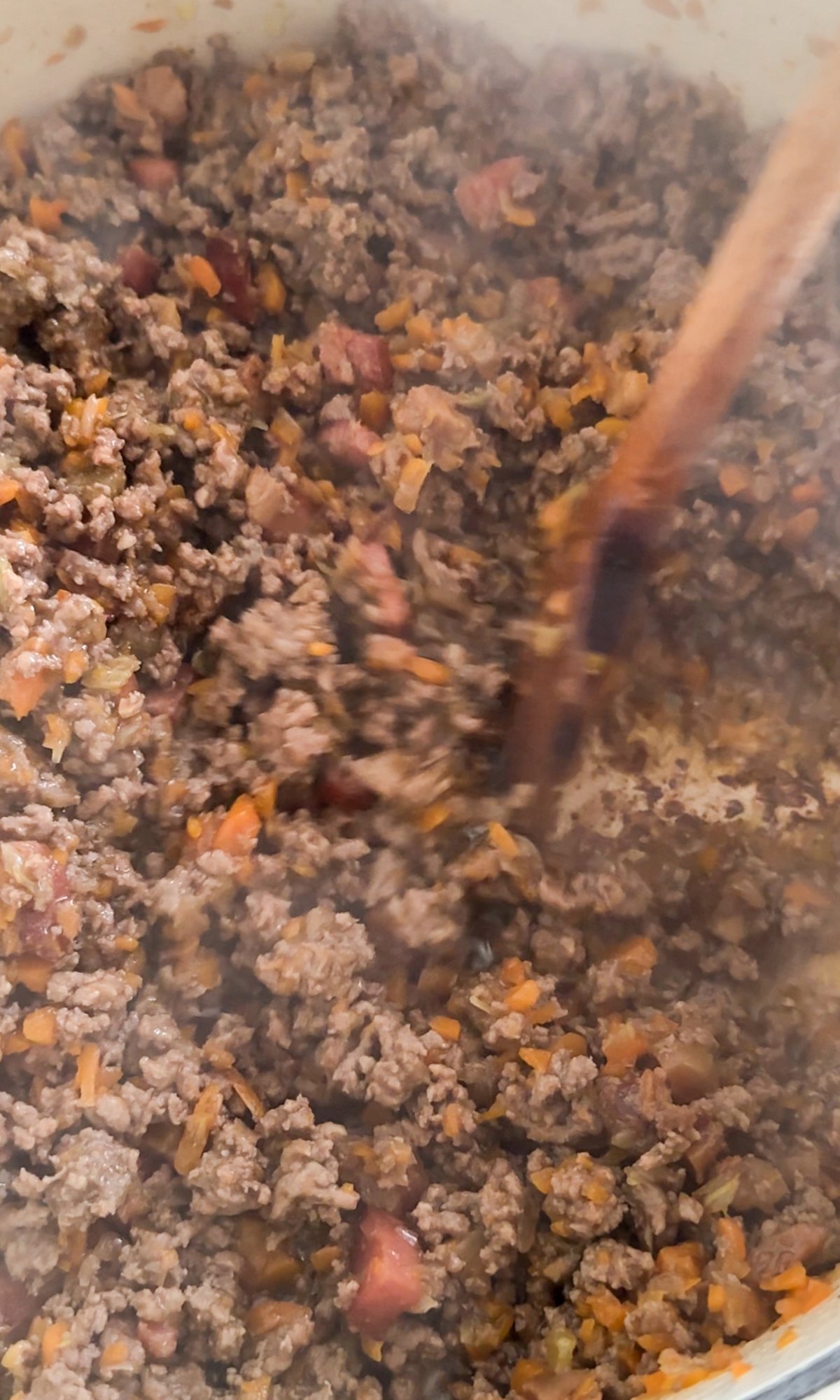 Browned ground beef, pancetta and soffritto in a pot being stirred
