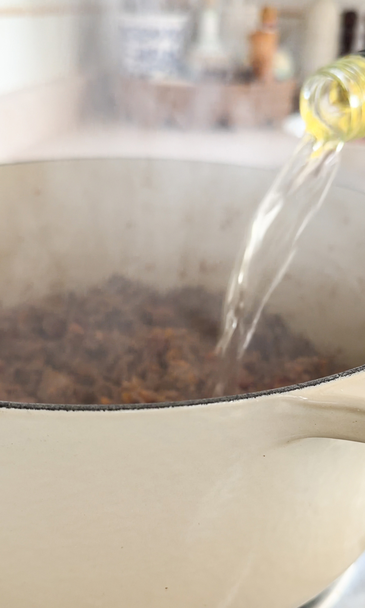 White wine being poured into a pot with meat in it