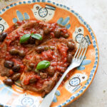 Plate of steak pizzaiola with dried oregano in the background