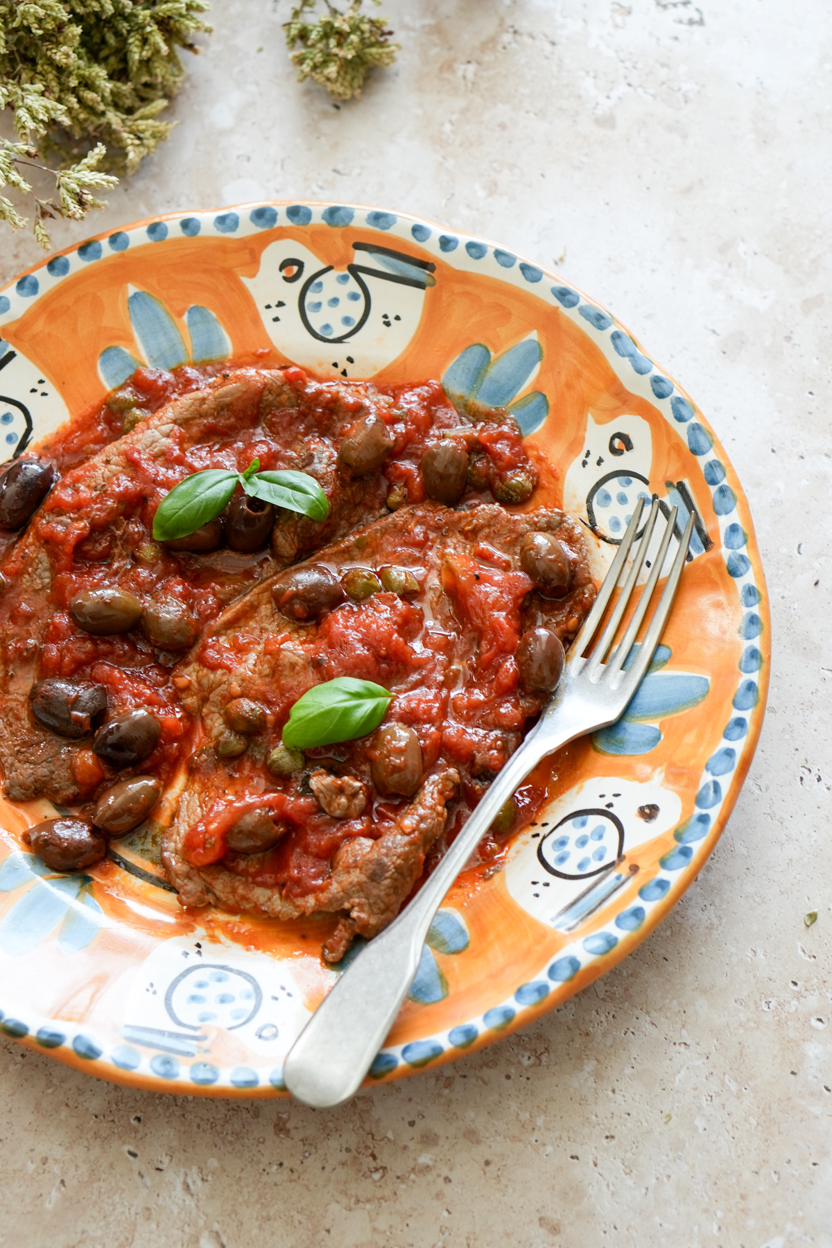 Plate of steak pizzaiola with dried oregano in the background