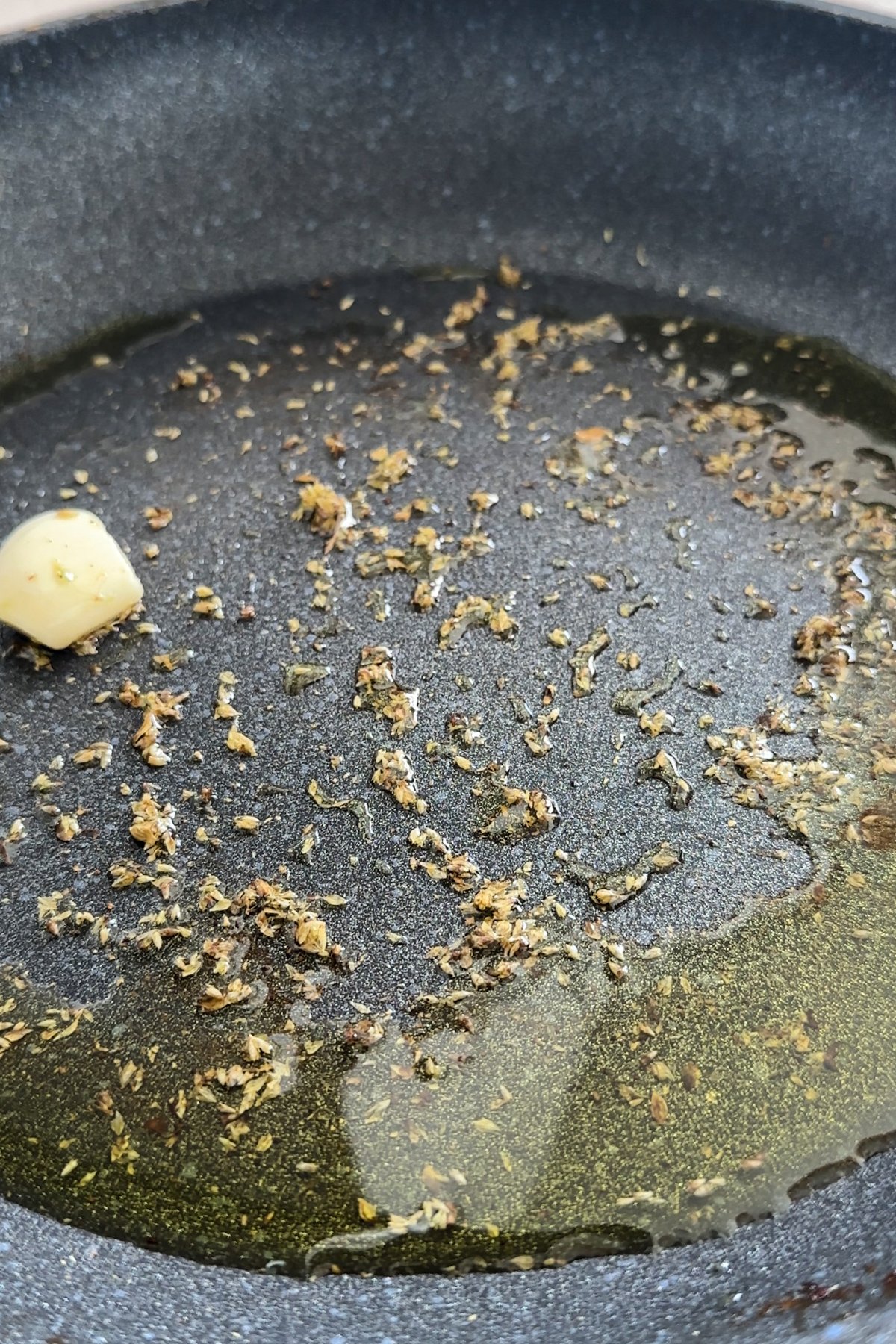 Dried oregano with olive oil and garlic clove in a pan