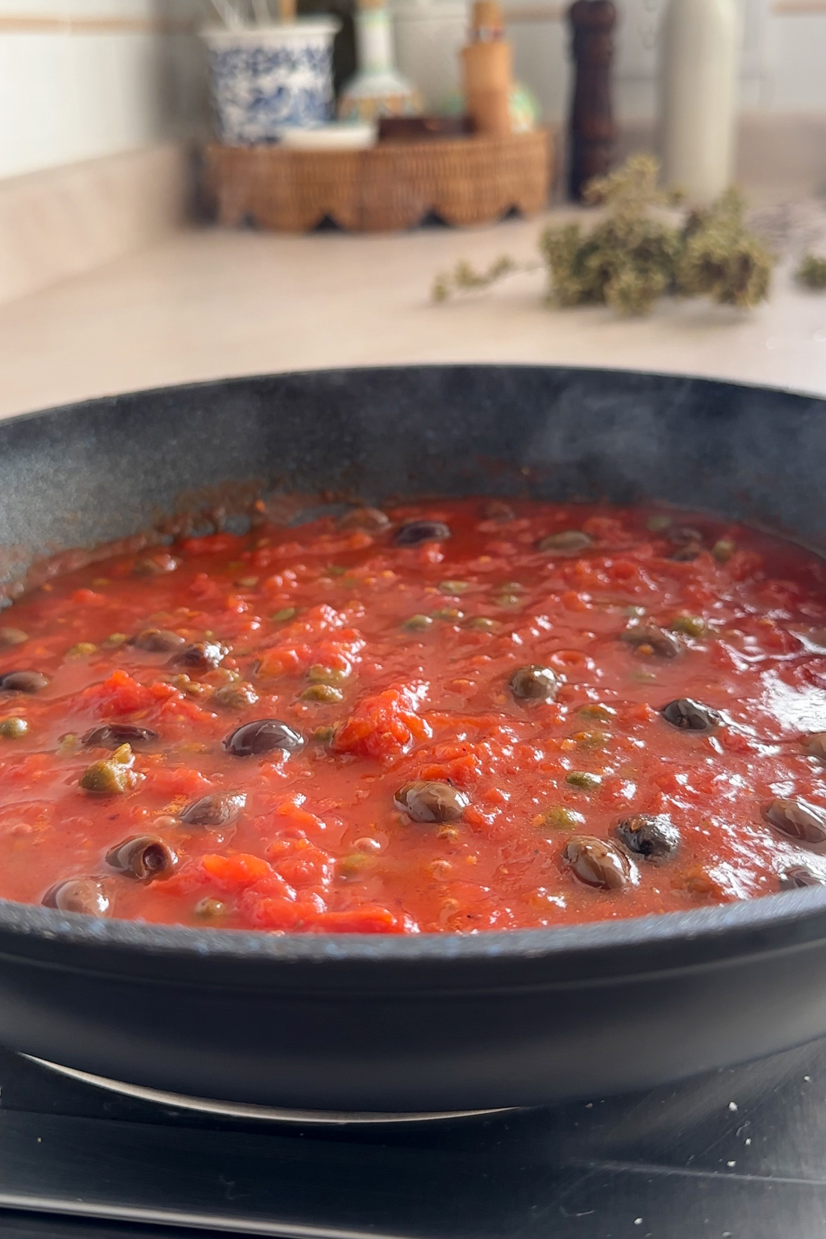Cooked tomato sauce in a pan with olives and capers