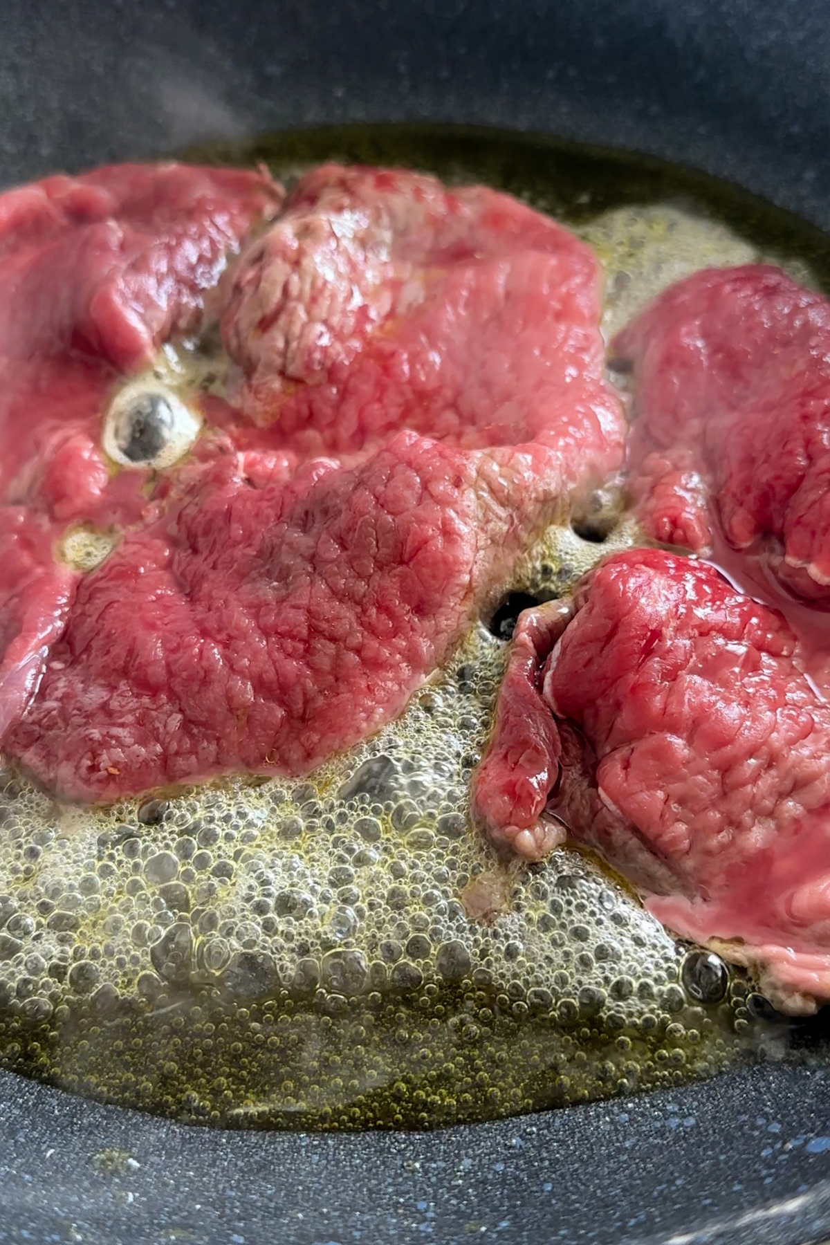 Thin cut sirloin steaks in a pan being cooked