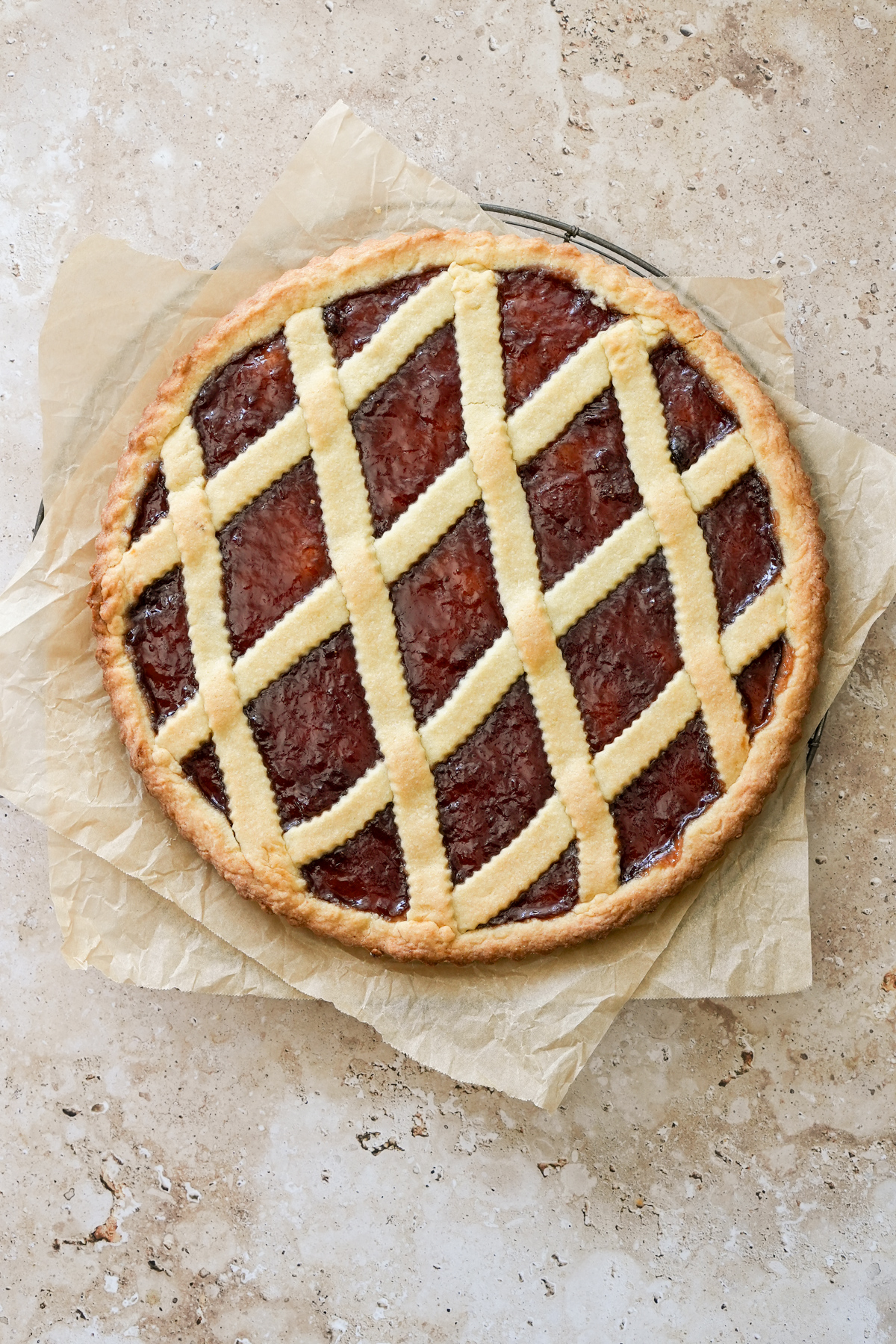 Jam Crostata - a classic Italian jam tart. Yum! #pinacooks #crostata #jamcrostata #italiandesserts #italianfood Whole crostata on a cooling rack with parchment paper