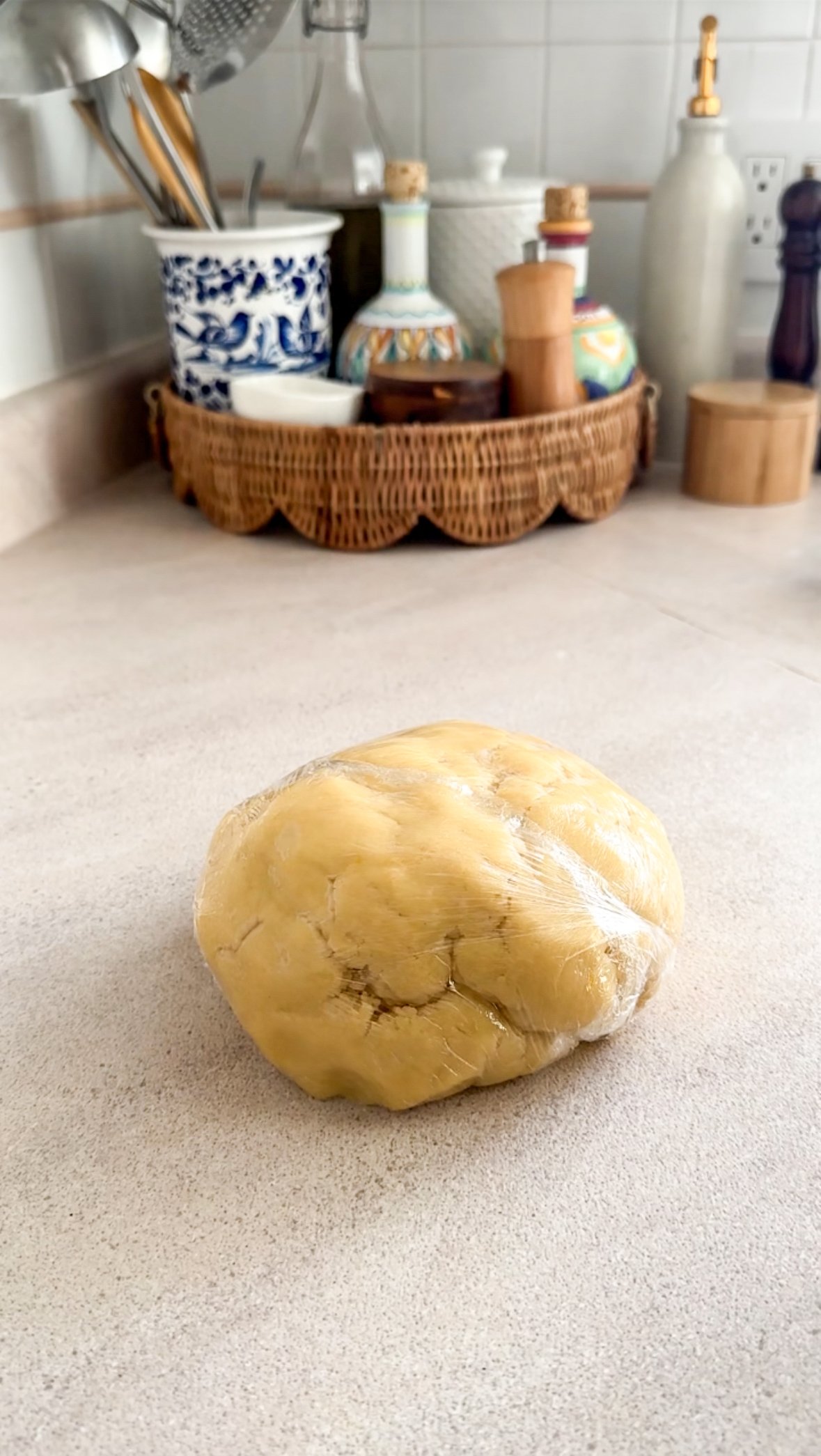 Crostata dough formed into a ball on work surface wrapped in plastic wrap