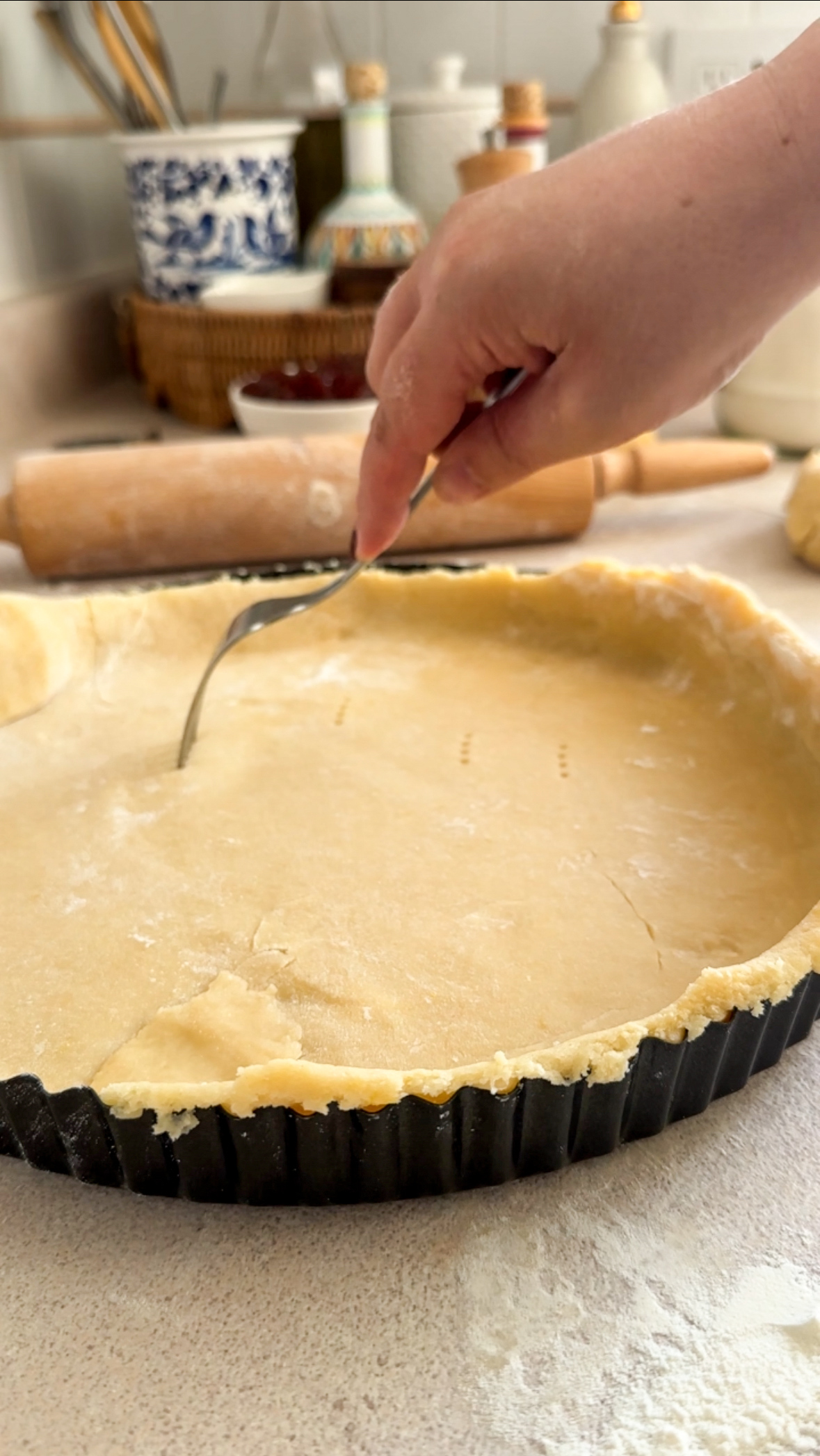 Crostata dough in tart pan being poked with a fork