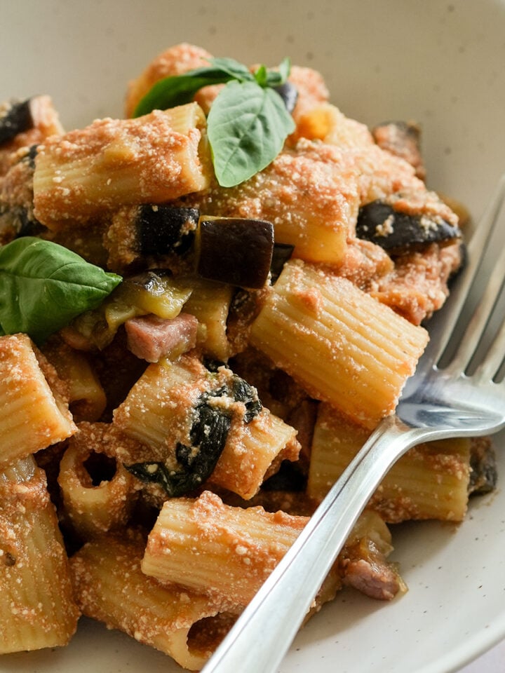 eggplant and ricotta pasta in a dish topped with fresh basil leaves