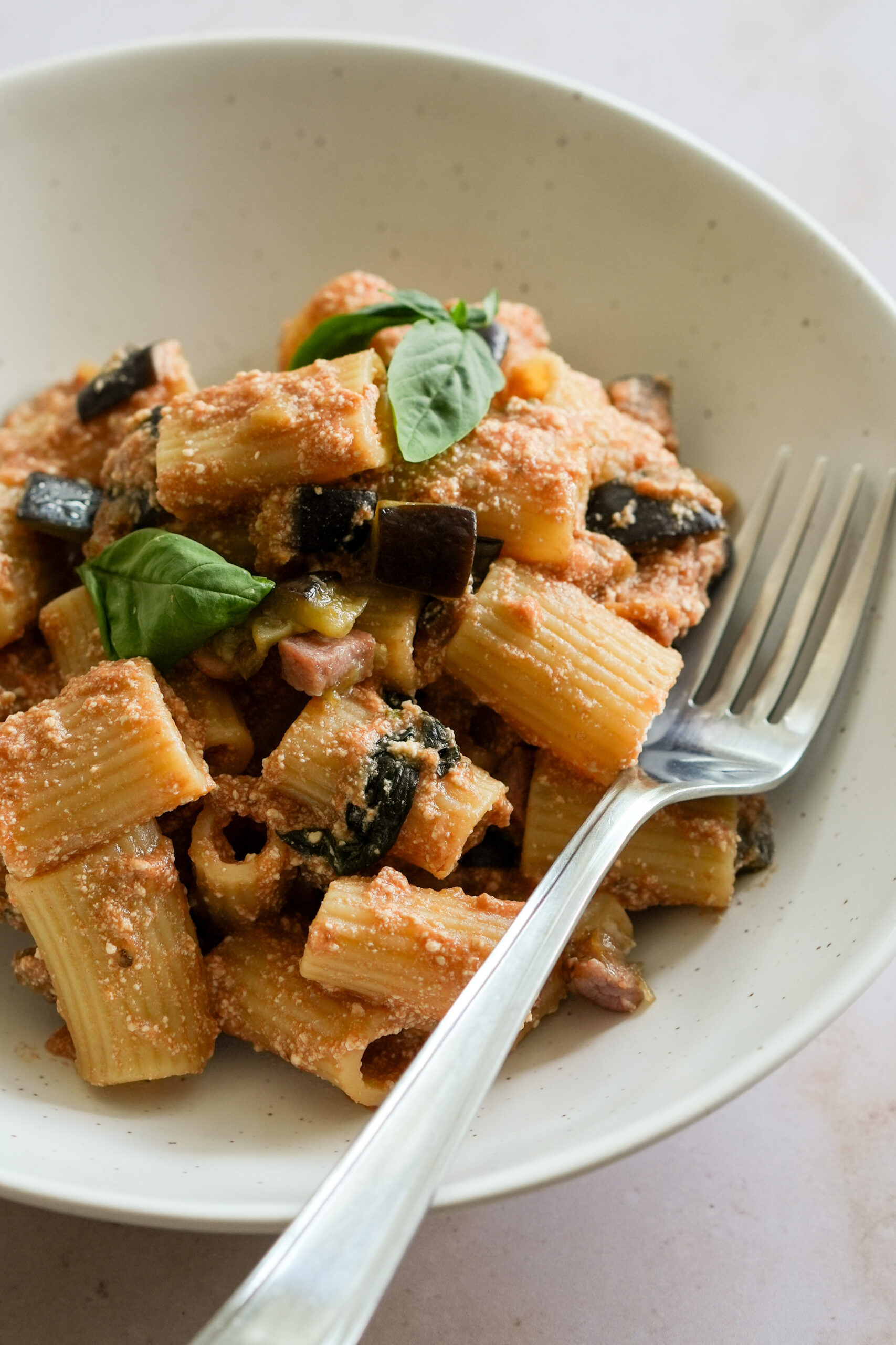 eggplant and ricotta pasta in a bowl topped with fresh basil