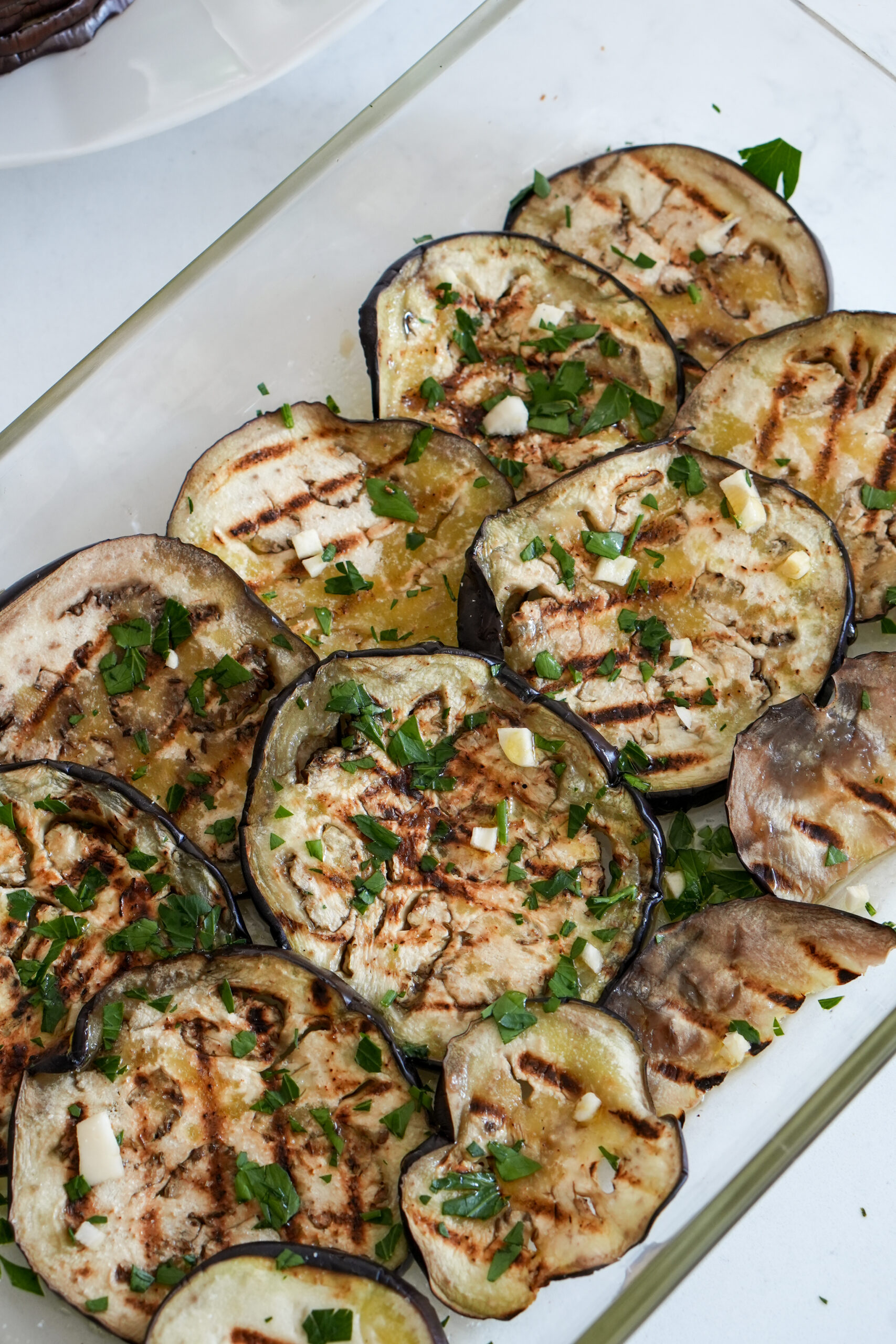 Grilled eggplant rounds in a glass baking dish