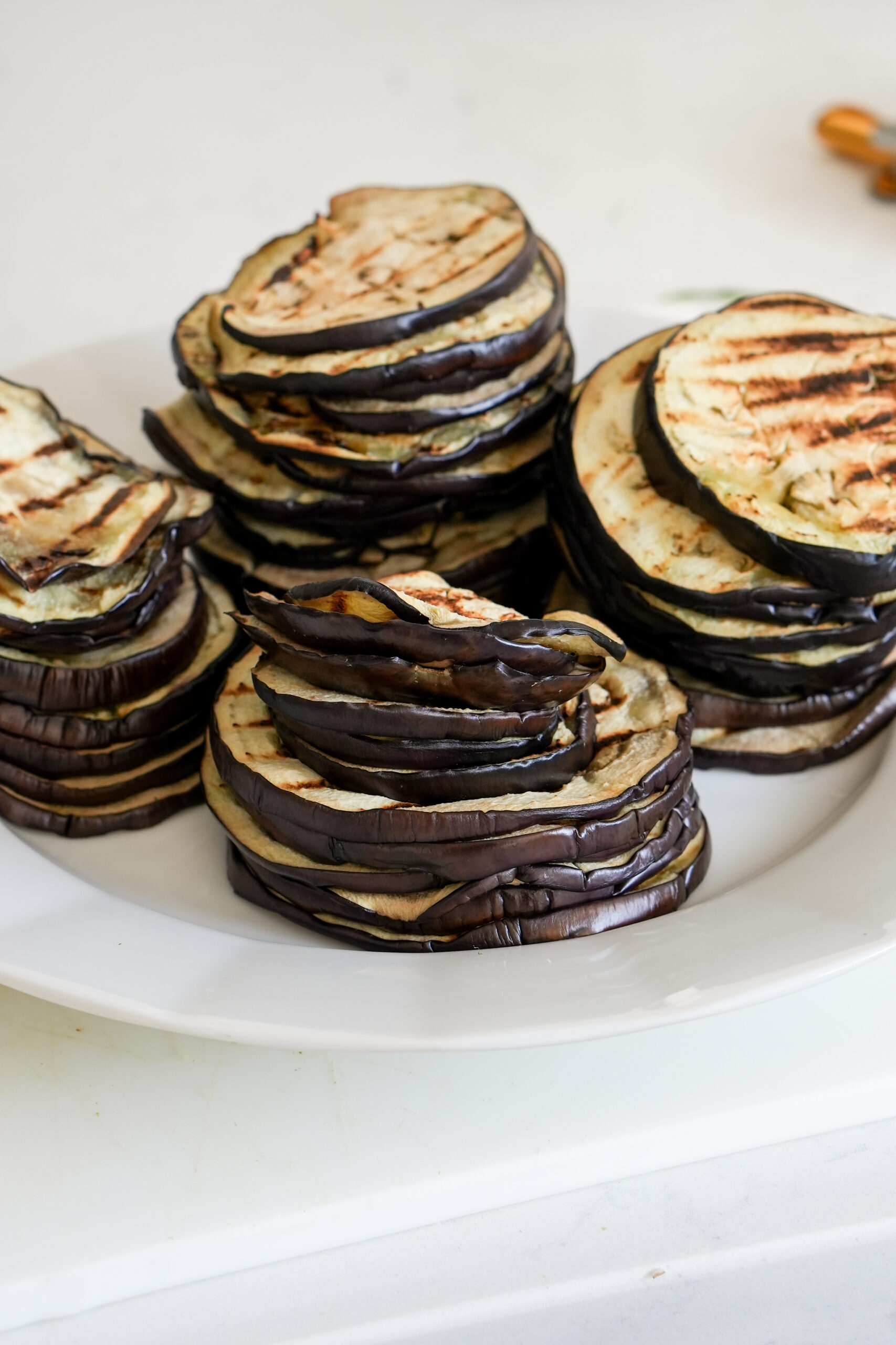 Grilled eggplant rounds in a dish stacked on top of each other