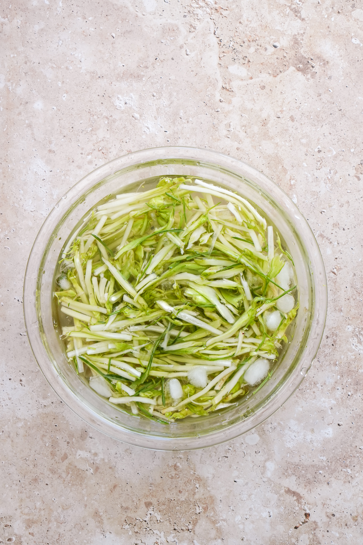 Julienned puntarelle in a glass bowl with water and ice
