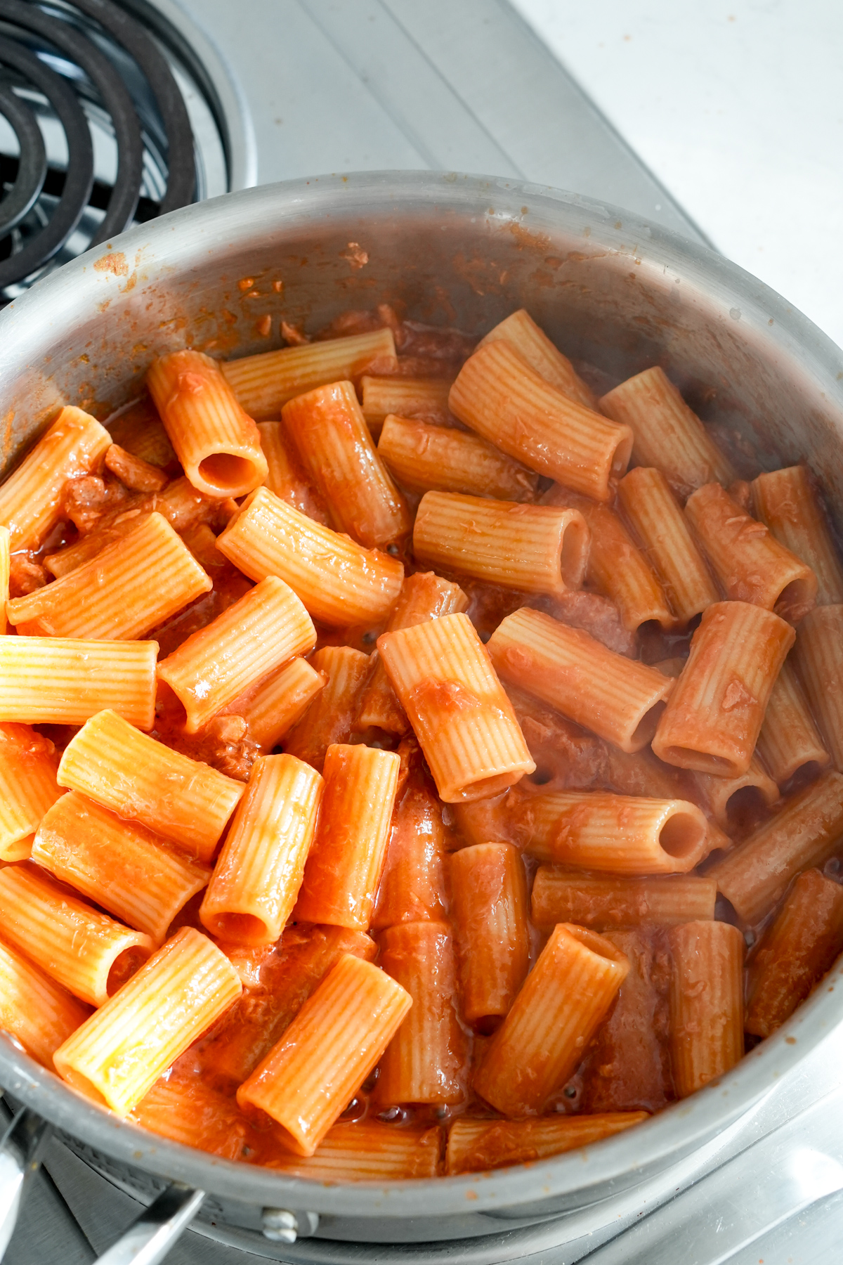 Rigatoni pasta mixed with canned tuna tomato sauce in a pan